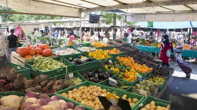 Un étalage de fruits et légumes dans un marché en extérieur.
