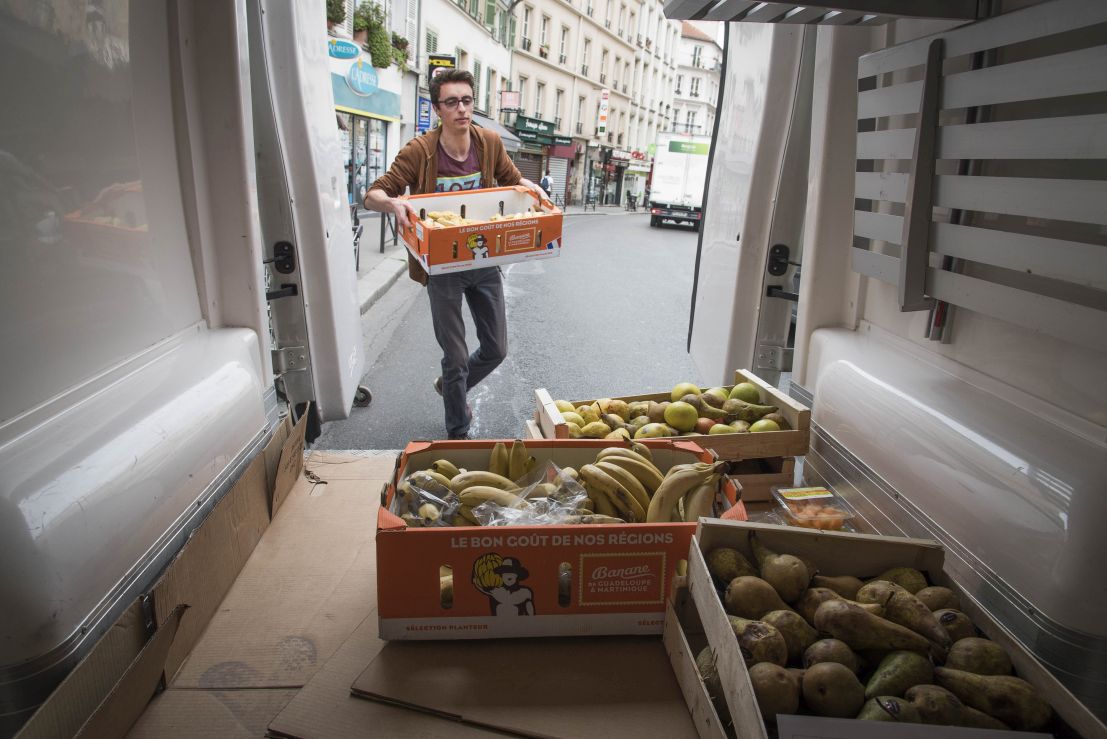 Homme portant un cageot de bananes et s’apprêtant à le stocker dans une camionnette