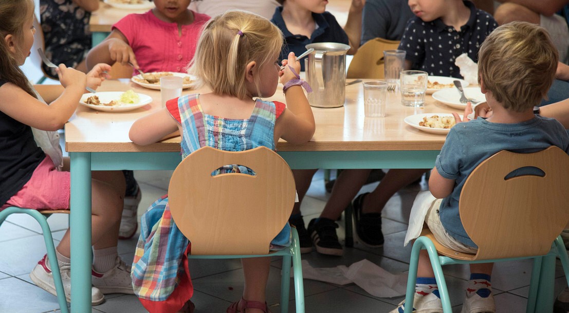 Un groupe d'enfants en train de manger à la cantine scolaire.