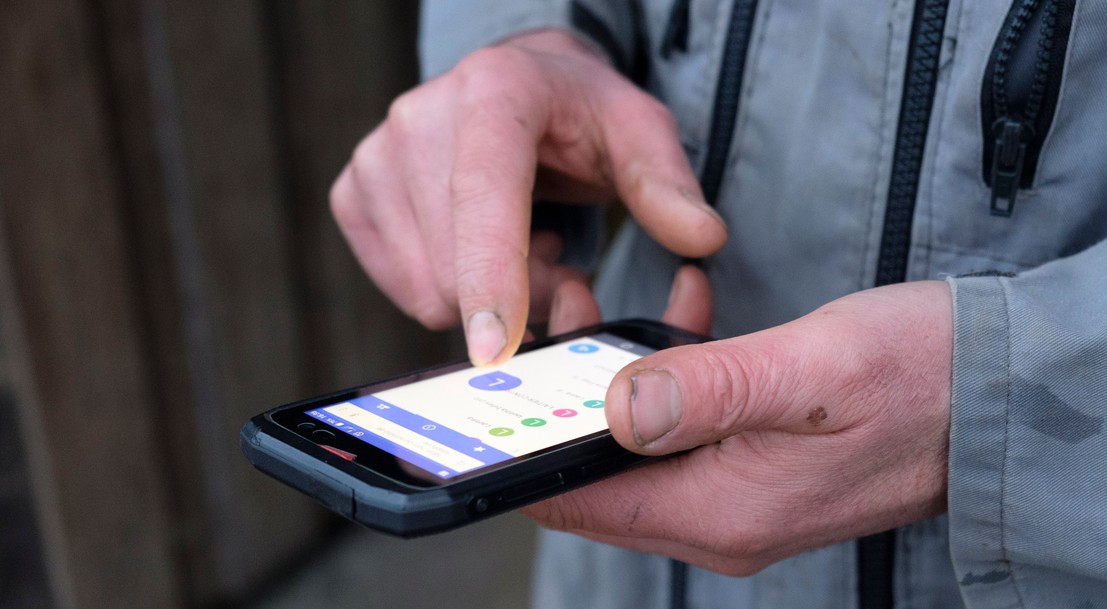 gros plan de la main d'un agriculteur manipulant un smartphone 