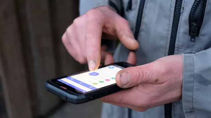 gros plan de la main d'un agriculteur manipulant un smartphone