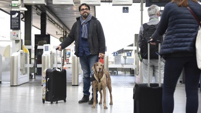 Voyageur dans une gare avec son chien