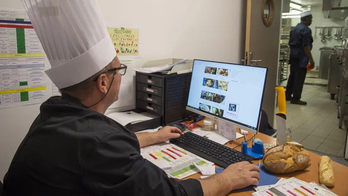 Le chef d'une cantine devant un ordinateur