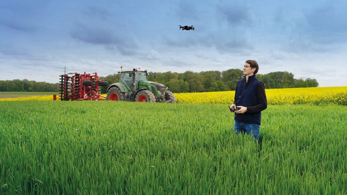 A farmer flying a drone in a field