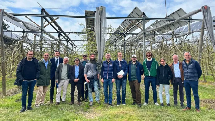 Groupe de personnes posant devant des infrastructures d'agrivoltaïsme